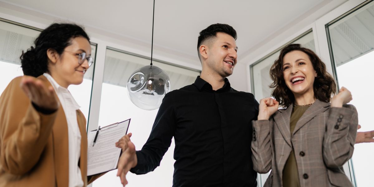 Smiling couple celebrating with a realtor after closing a home deal.