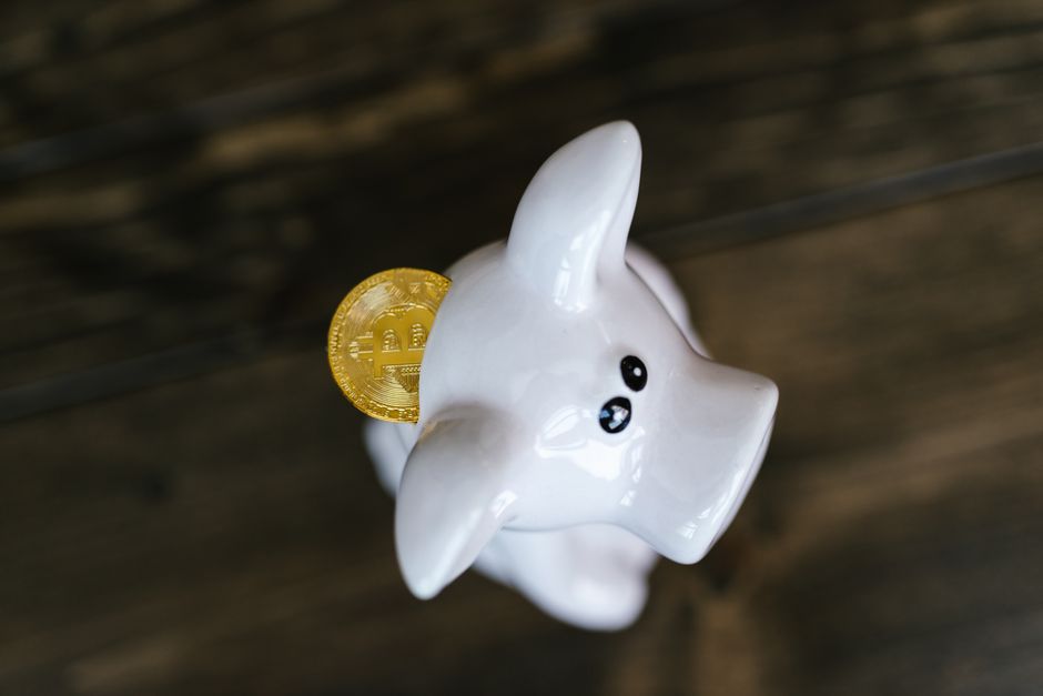 Modern house key and a white ceramic piggy bank resting on a clean, bright desk, symbolizing the concept of saving money o...